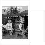 1960s Boy Playing Guitar, Woman Holding Soft Drink Bottle Outside In Backyard by Anonymous