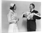 1930s 1940s Woman Nurse Talking With Man Proud New Father Holding Newborn Twin Babies by Anonymous