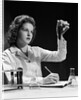 1940s Student Nurse Holding Up Test Tube While Taking Notes In Science Class by Anonymous