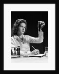 1940s Student Nurse Holding Up Test Tube While Taking Notes In Science Class by Anonymous