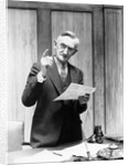 1930s Elderly Man In Office Standing Behind Desk Gesturing With Raised Finger by Anonymous
