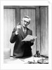 1930s Elderly Man In Office Standing Behind Desk Gesturing With Raised Finger by Anonymous