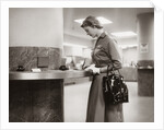 1950s 1960s Woman Handbag On Arm Gloves Filling Out Deposit Slip Bank Counter by Anonymous