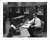 1960s Man In Shirt Tie and Thick Black Glasses Working With IBM Data Processing System by Anonymous