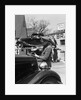 1930s Service Station Attendant In Cap and Coveralls Pouring Water From Spouted Can Into Automobile Radiator by Anonymous