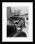 1930s Service Station Attendant In Cap and Coveralls Pouring Water From Spouted Can Into Automobile Radiator by Anonymous