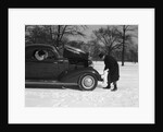 Woman Passenger Watching Man Motorist Try To Crank Start A Chevrolet Coupe Stalled In Snow by Anonymous