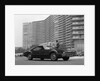 1960s Man In Suit and Hat Standing Beside Oldsmobile Toranado In Front Of Large Apartment Building by Anonymous