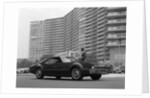 1960s Man In Suit and Hat Standing Beside Oldsmobile Toranado In Front Of Large Apartment Building by Anonymous