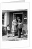 1950s Suburban Mom At Home Front Door With Son Watching Receiving Package From Mailman by Anonymous
