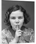 1930s Portrait Of Young Girl With Finger To Mouth Making Shush Be Quiet Expression by Anonymous