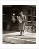 1950s Businessman On Railroad Station Platform Reading Newspaper Waiting For Train by Anonymous