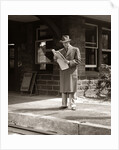 1950s Businessman On Railroad Station Platform Reading Newspaper Waiting For Train by Anonymous