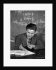 1920s 1930s Boy At Desk In Classroom In Front Of Blackboard Shooting Paper Wad With Rubber Band by Anonymous