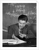 1920s 1930s Boy At Desk In Classroom In Front Of Blackboard Shooting Paper Wad With Rubber Band by Anonymous