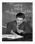 1920s 1930s Boy At Desk In Classroom In Front Of Blackboard Shooting Paper Wad With Rubber Band by Anonymous