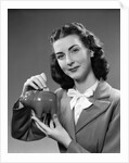 1940s Woman Putting Change Into Piggy Bank by Anonymous