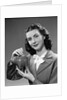 1940s Woman Putting Change Into Piggy Bank by Anonymous