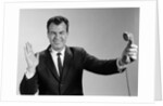 1960s Businessman Holding Telephone At Arms Length With Expression Of Disgust Or Rejection by Anonymous