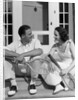 1930s Couple Man Woman In Tennis Whites Holding Racquets Sitting Talking On Steps In Front Of House Outdoor by Anonymous