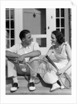 1930s Couple Man Woman In Tennis Whites Holding Racquets Sitting Talking On Steps In Front Of House Outdoor by Anonymous