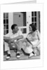 1930s Couple Man Woman In Tennis Whites Holding Racquets Sitting Talking On Steps In Front Of House Outdoor by Anonymous