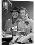 1950s Husband And Wife Carrying Armload Of Christmas Packages Standing In Snow Under Porch Light by Anonymous