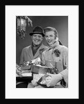 1950s Husband And Wife Carrying Armload Of Christmas Packages Standing In Snow Under Porch Light by Anonymous