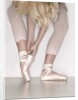 Ballerina adjusting toe shoe by Anonymous
