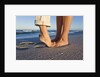 Feet of couple hugging on beach by Anonymous
