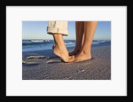 Feet of couple hugging on beach by Anonymous