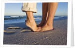 Feet of couple hugging on beach by Anonymous
