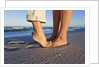 Feet of couple hugging on beach by Anonymous