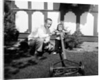 A father show his two year old daughter how to mow the lawn, ca. 1956 by Anonymous