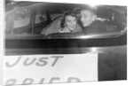A couple peers out of the back window on their wedding day, ca. 1953 by Anonymous