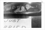 A couple peers out of the back window on their wedding day, ca. 1953 by Anonymous
