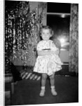 A little girl stands by the Christmas tree clutching her doll, ca. 1955 by Anonymous