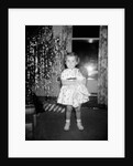 A little girl stands by the Christmas tree clutching her doll, ca. 1955 by Anonymous