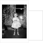 A little girl stands by the Christmas tree clutching her doll, ca. 1955 by Anonymous