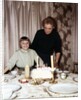 Nine year old girl is about to blow out the candles on her while her mom watches, ca. 1962 by Anonymous