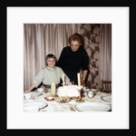 Nine year old girl is about to blow out the candles on her while her mom watches, ca. 1962 by Anonymous