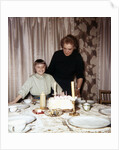 Nine year old girl is about to blow out the candles on her while her mom watches, ca. 1962 by Anonymous