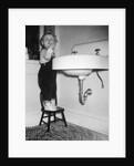 A young girl brushes her teeth at the sink, ca. 1955 by Anonymous