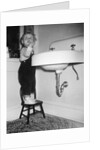 A young girl brushes her teeth at the sink, ca. 1955 by Anonymous