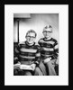 Two brothers pose with a book on their living room couch, ca. 1953 by Anonymous