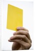 Hand holding yellow card by Anonymous