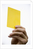 Hand holding yellow card by Anonymous