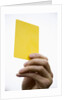 Hand holding yellow card by Anonymous