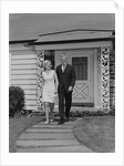 Mature couple walking on sidewalk front of house by Anonymous