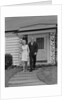 Mature couple walking on sidewalk front of house by Anonymous